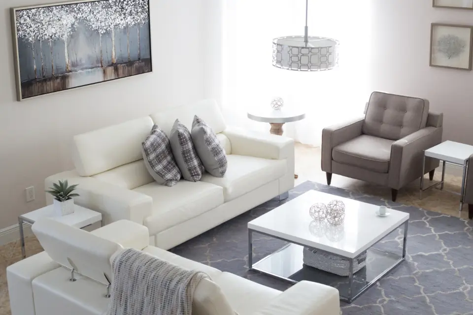 Helles, aufgeräumtes Wohnzimmer mit Sofa und Sessel